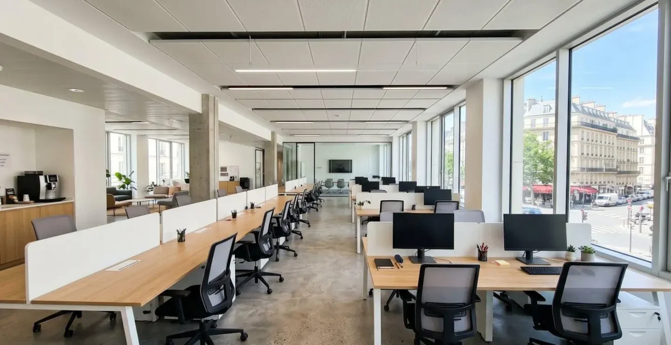 Open space contemporain français avec plusieurs postes de travail équipés de chaises ergonomiques noires, lumière naturelle abondante par de grandes fenêtres